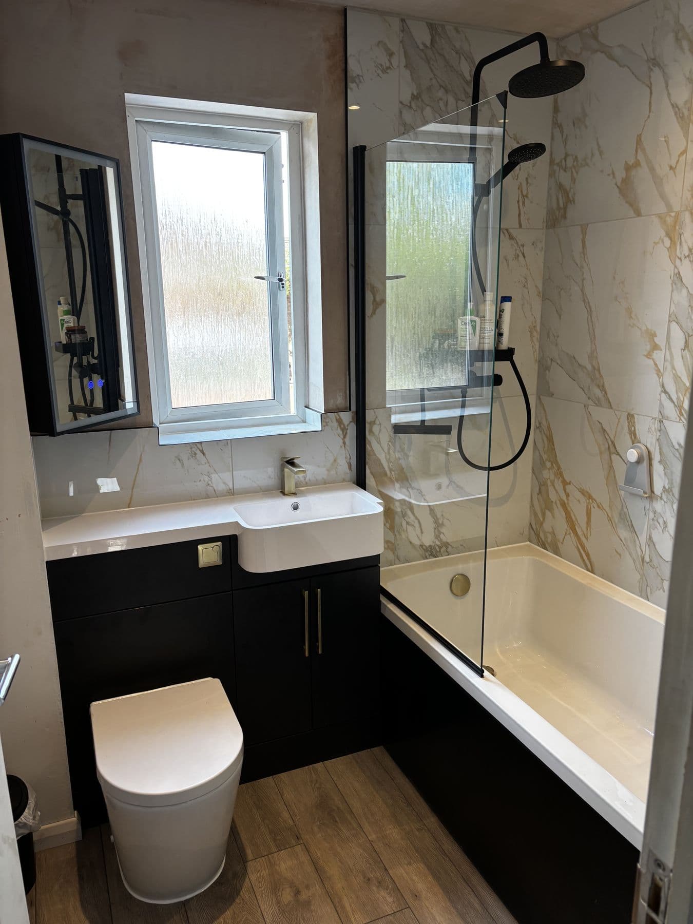 Bathroom renovation with bath, walk-in shower screen and marble tiled walls, Milton Keynes