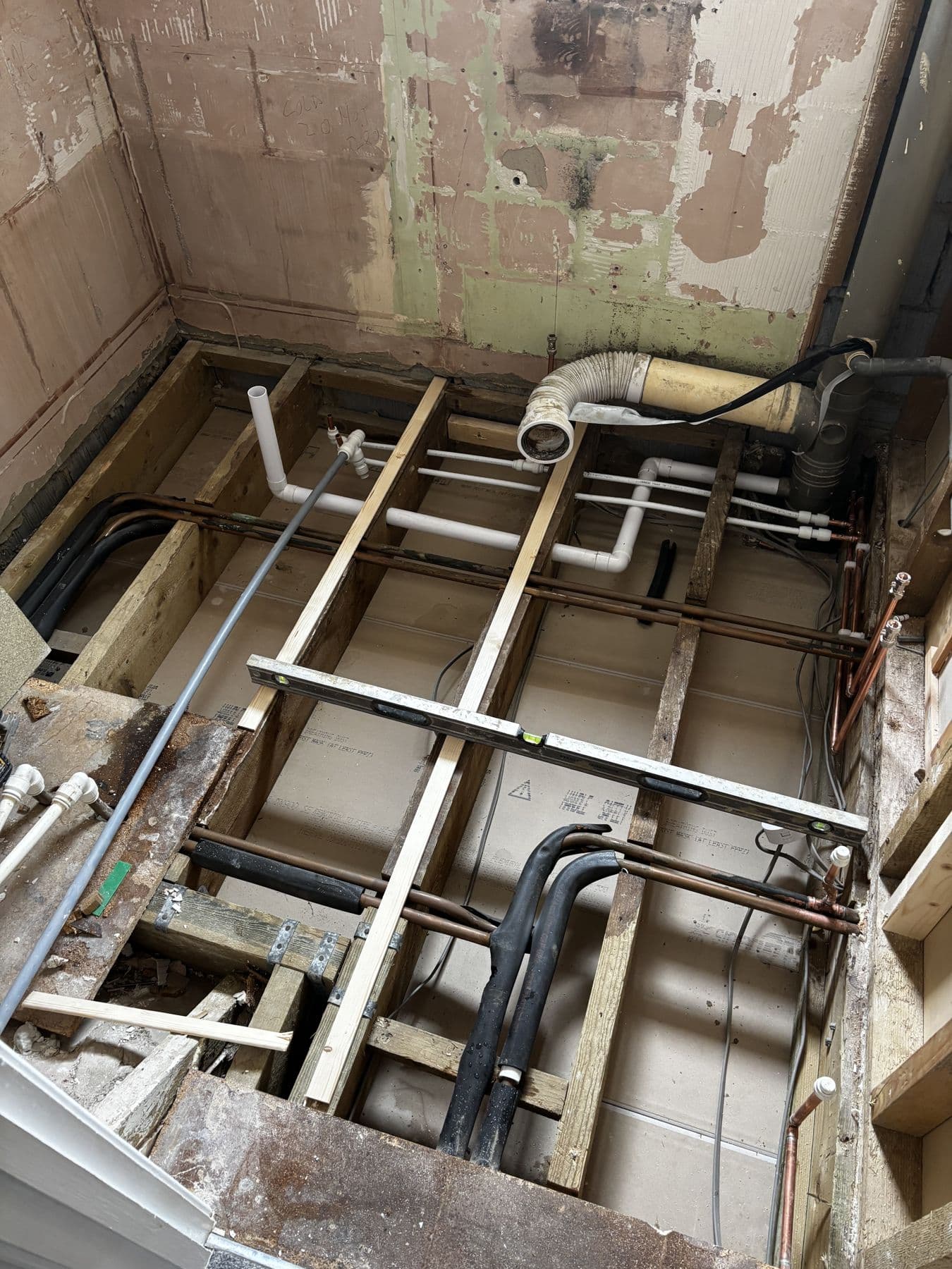 First fix plumbing under the bathroom floor with copper and plastic pipework laid between the joists
