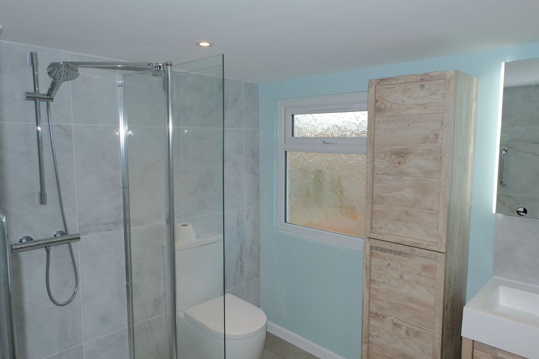 Bathroom with a walk-in shower, glass screen and wooden storage unit