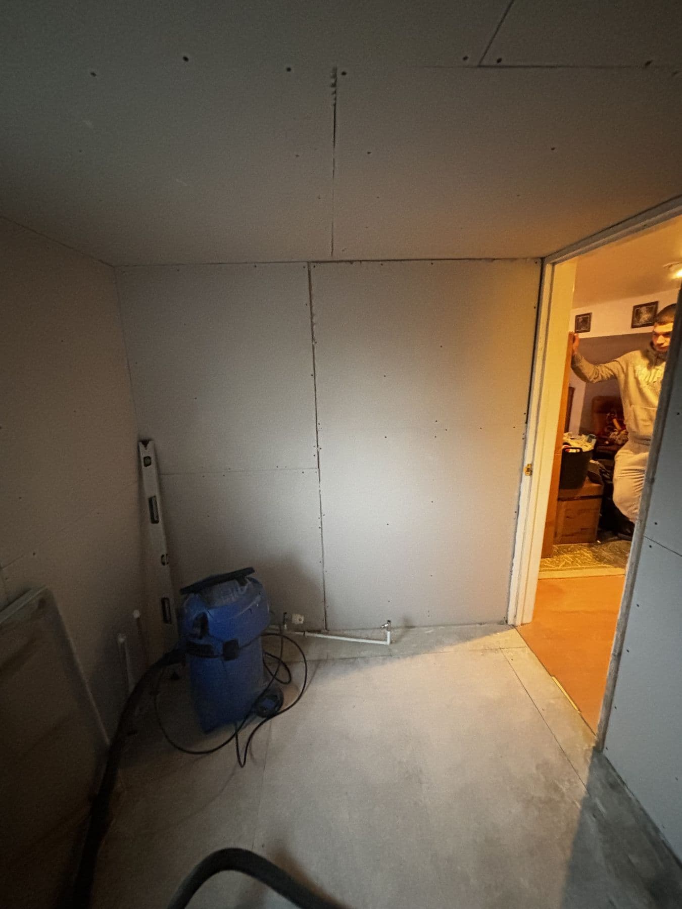 Room with plasterboard walls and ceiling and bare concrete floor during renovation