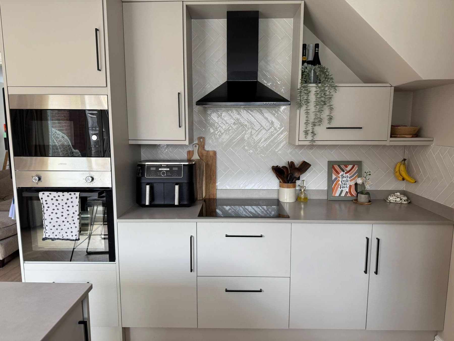 Soft grey kitchen with a herringbone tiled splashback and black handles