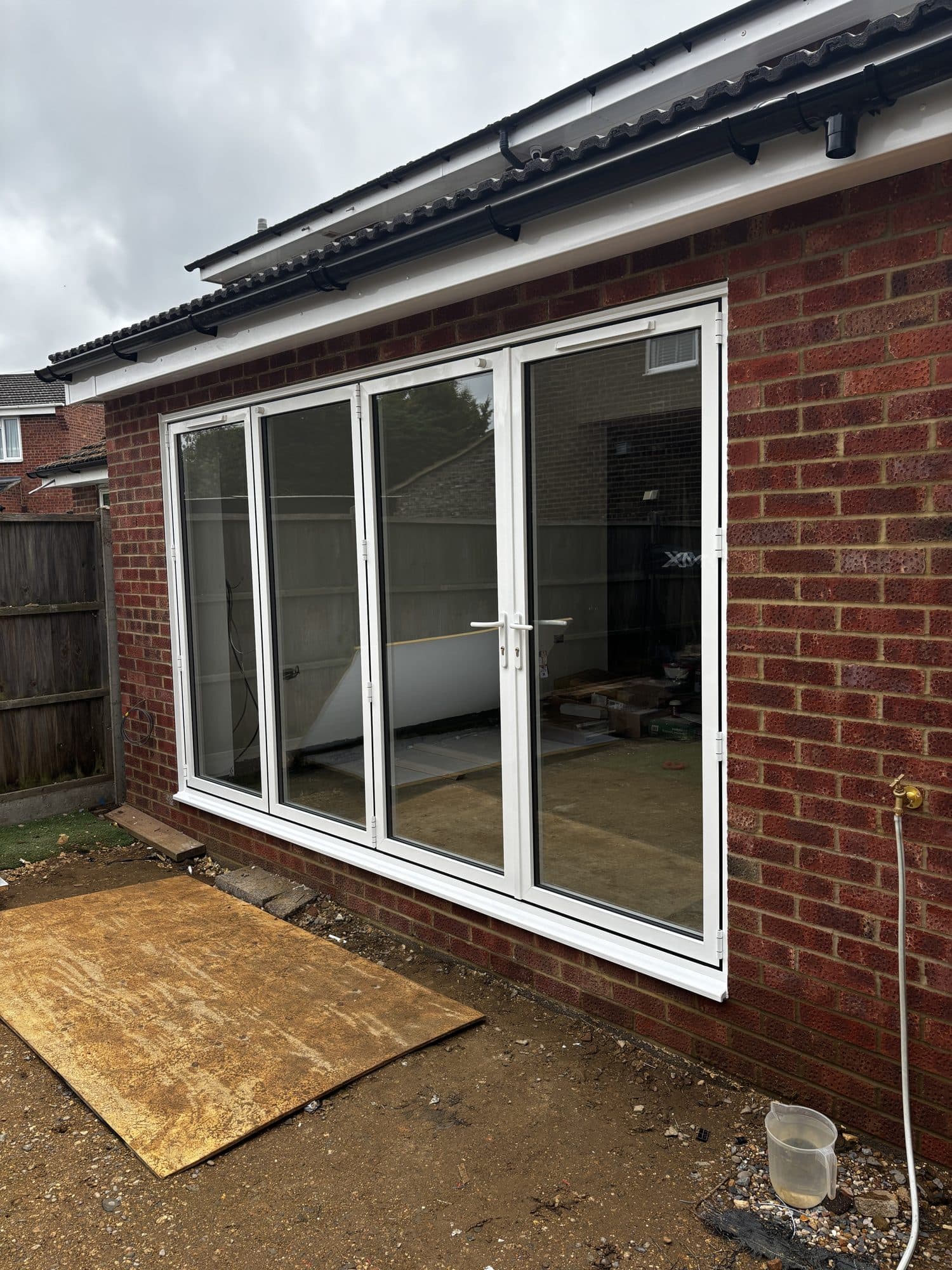 Exterior of the extension showing the four pane white bifold doors fitted into the brick rear wall