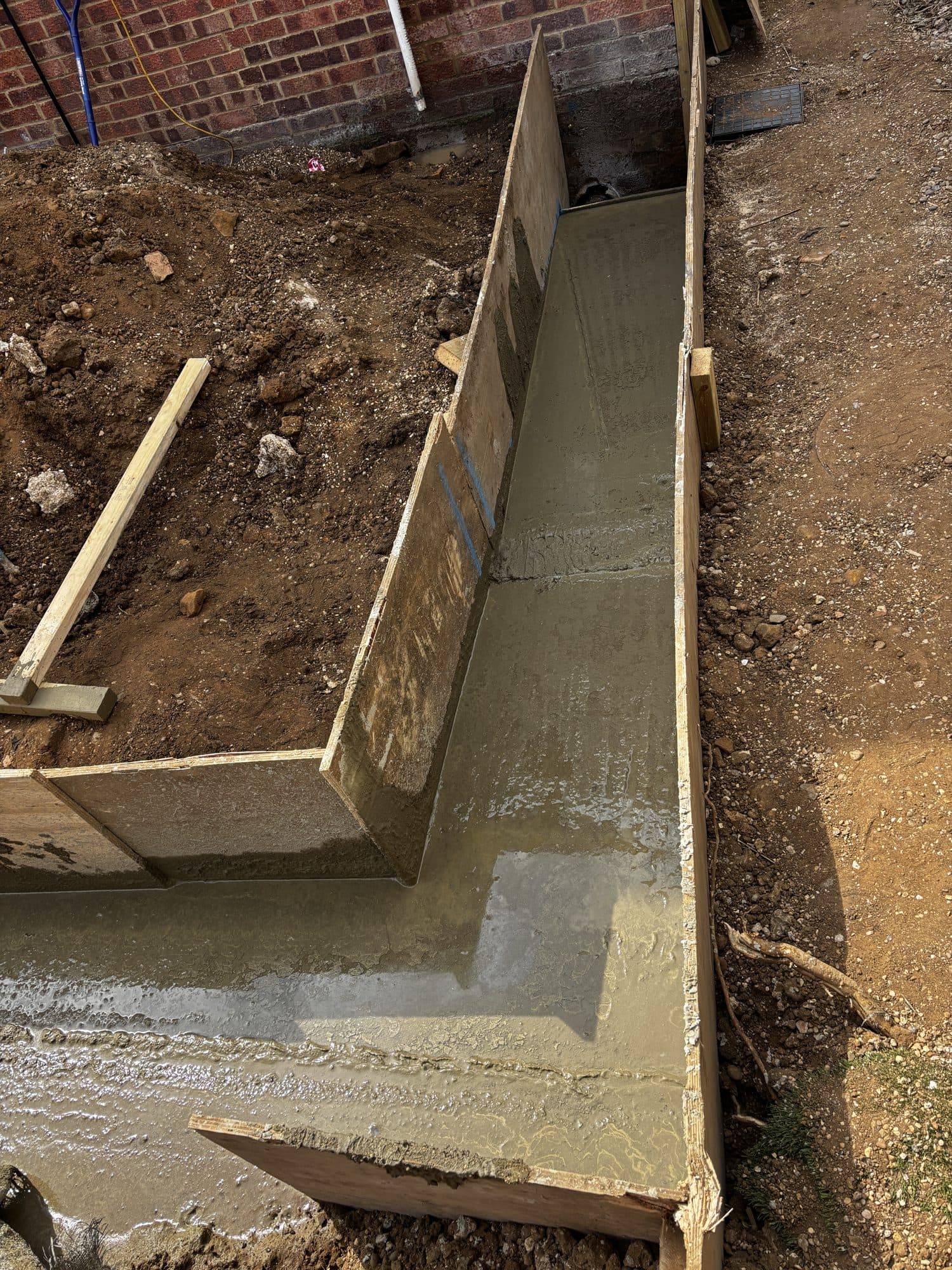 Concrete foundations being poured into timber shuttering for the extension footings