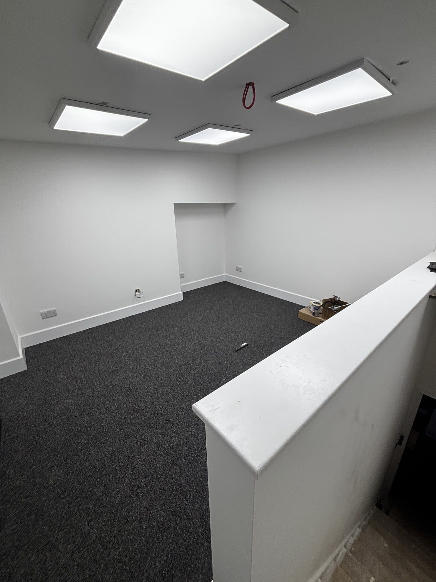 Finished office area viewed from a raised counter looking down over carpeted flooring and ceiling light panels