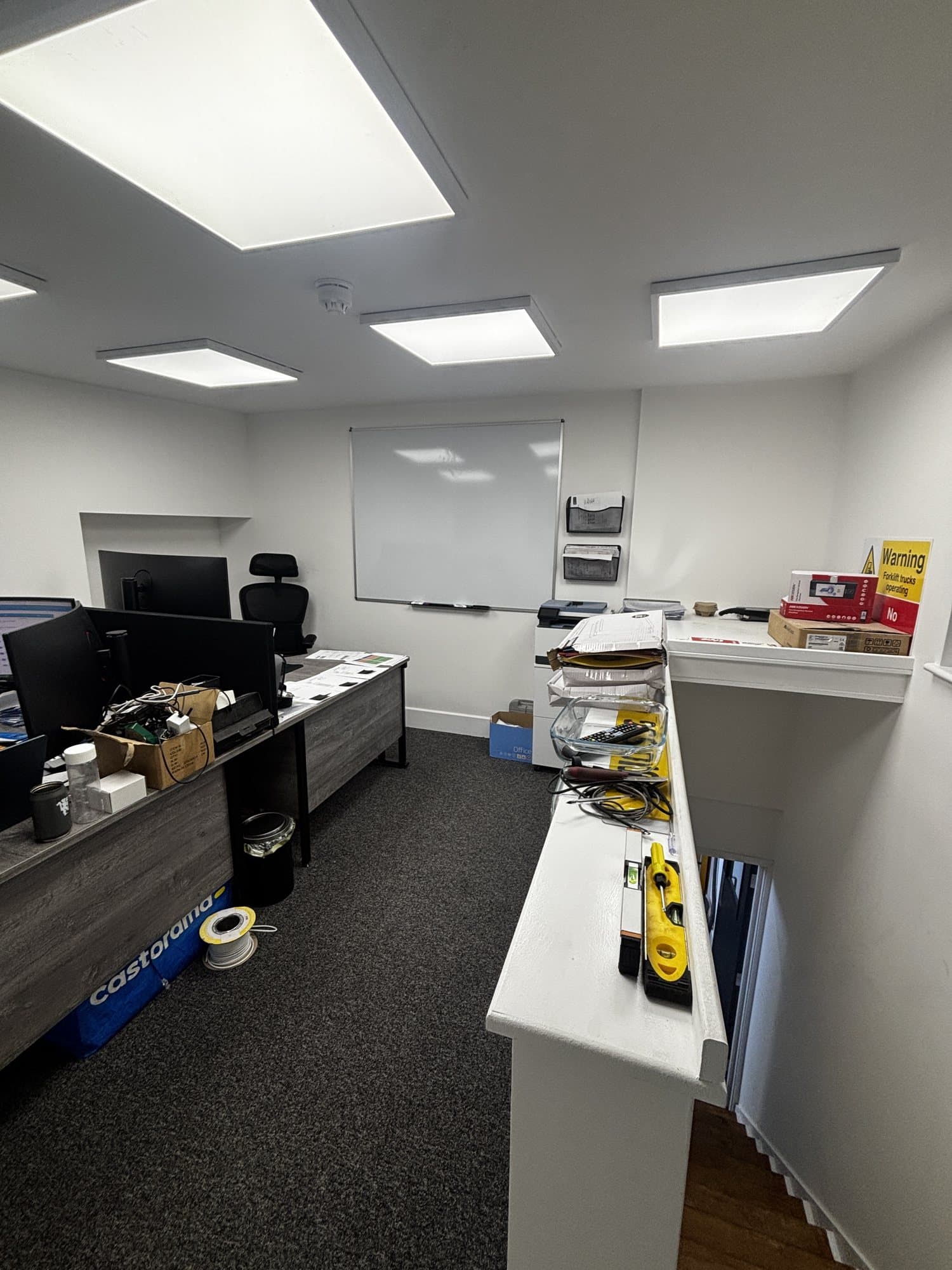 Finished office with desks, computer monitors, a whiteboard and a raised counter