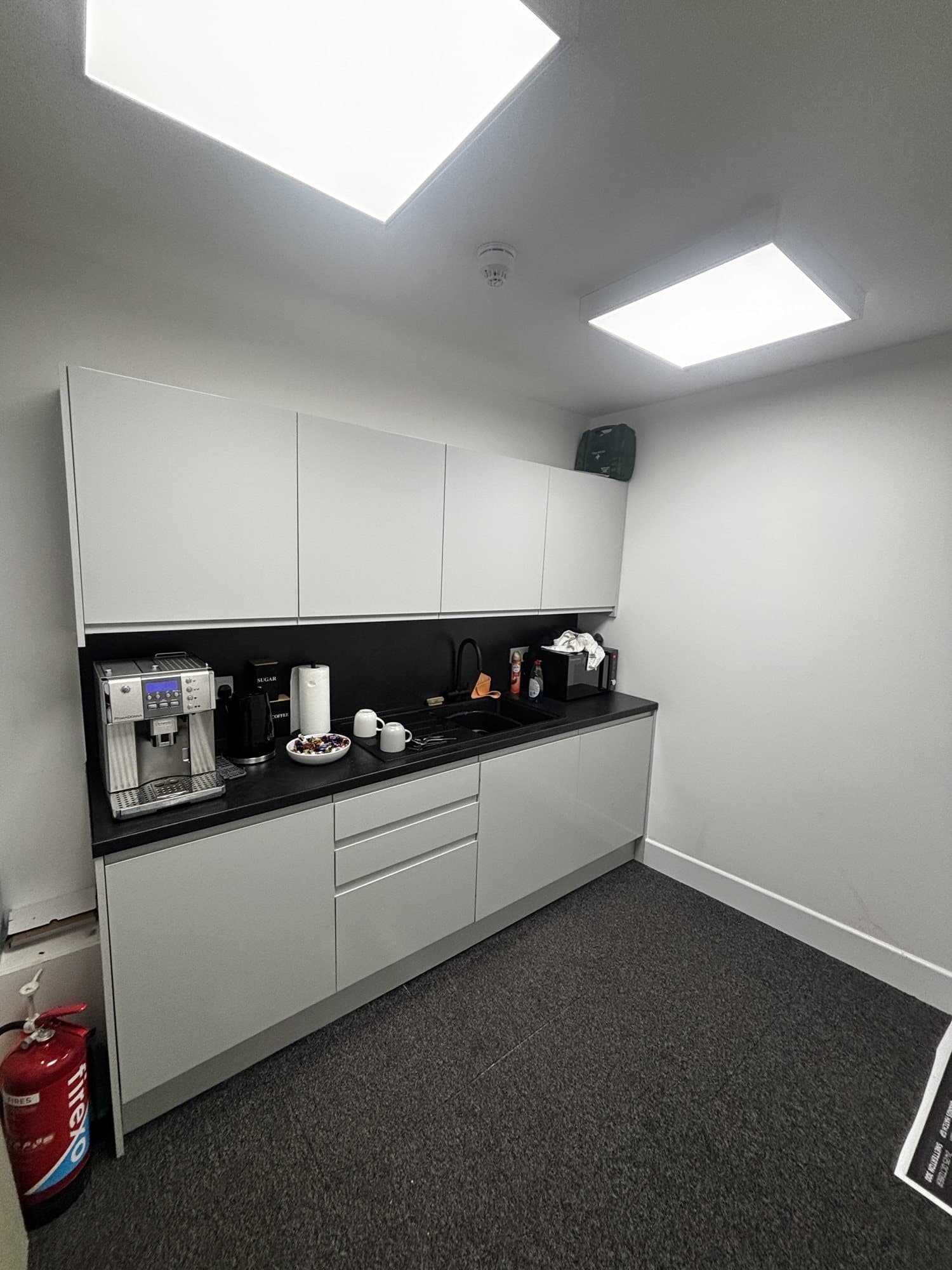 Finished kitchen with a coffee machine, kettle, black countertop and white cabinets