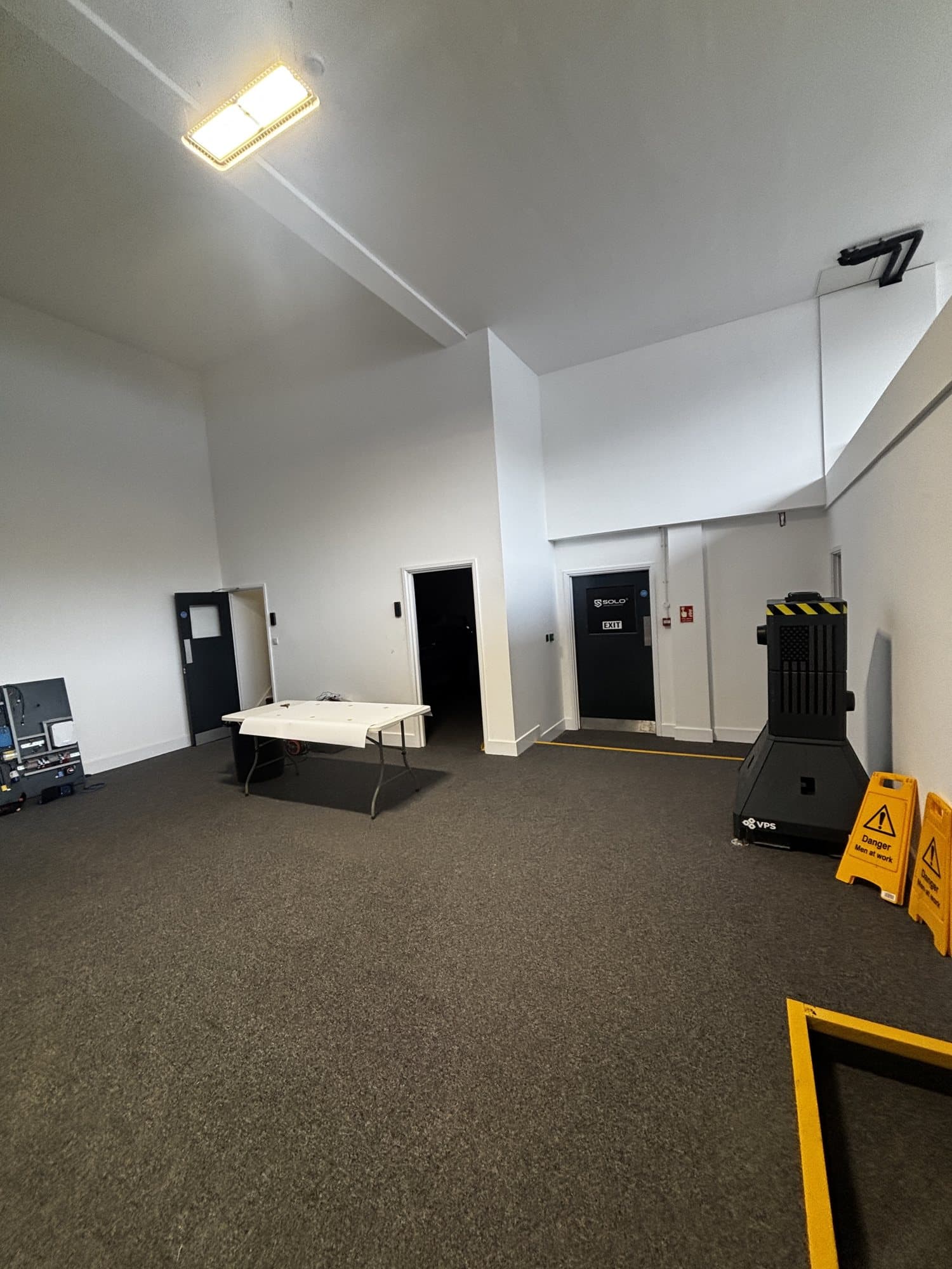 Finished open plan room with carpet flooring, a SOLO branded exit door and an air scrubber unit