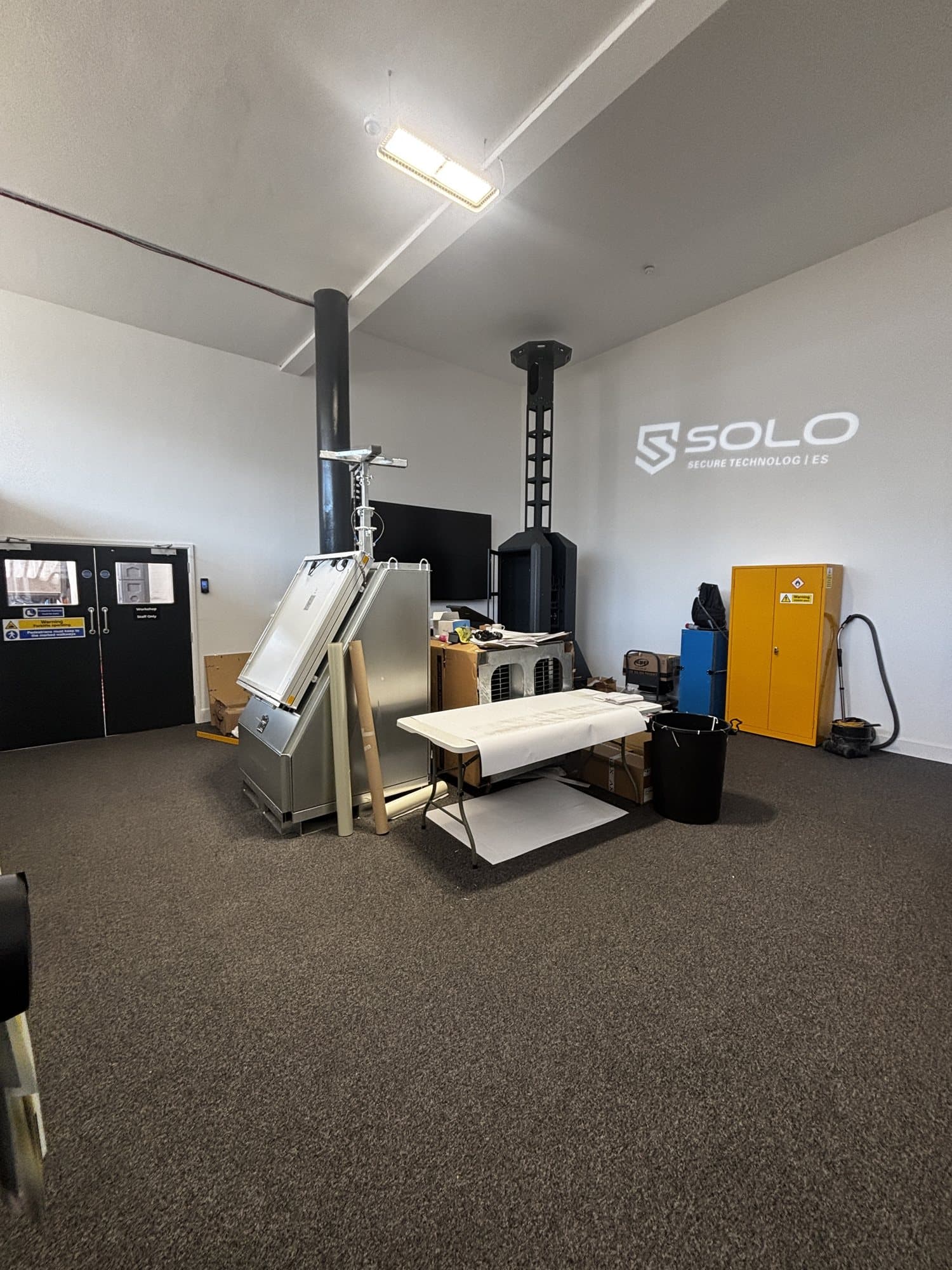 Finished room with the SOLO Secure Technologies logo on the wall, black double doors and storage cabinets