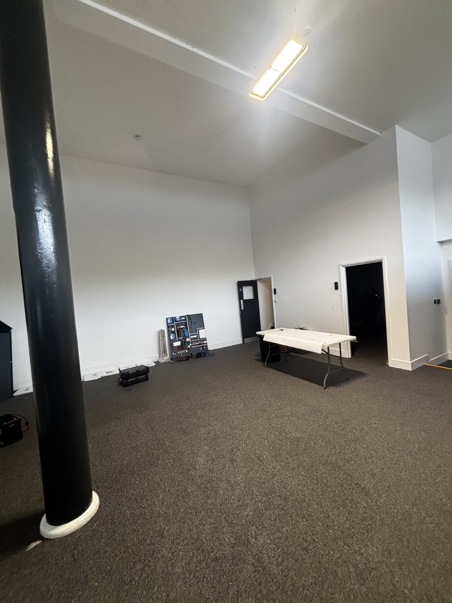 Finished open plan room with a black structural column, carpet flooring and a folding table
