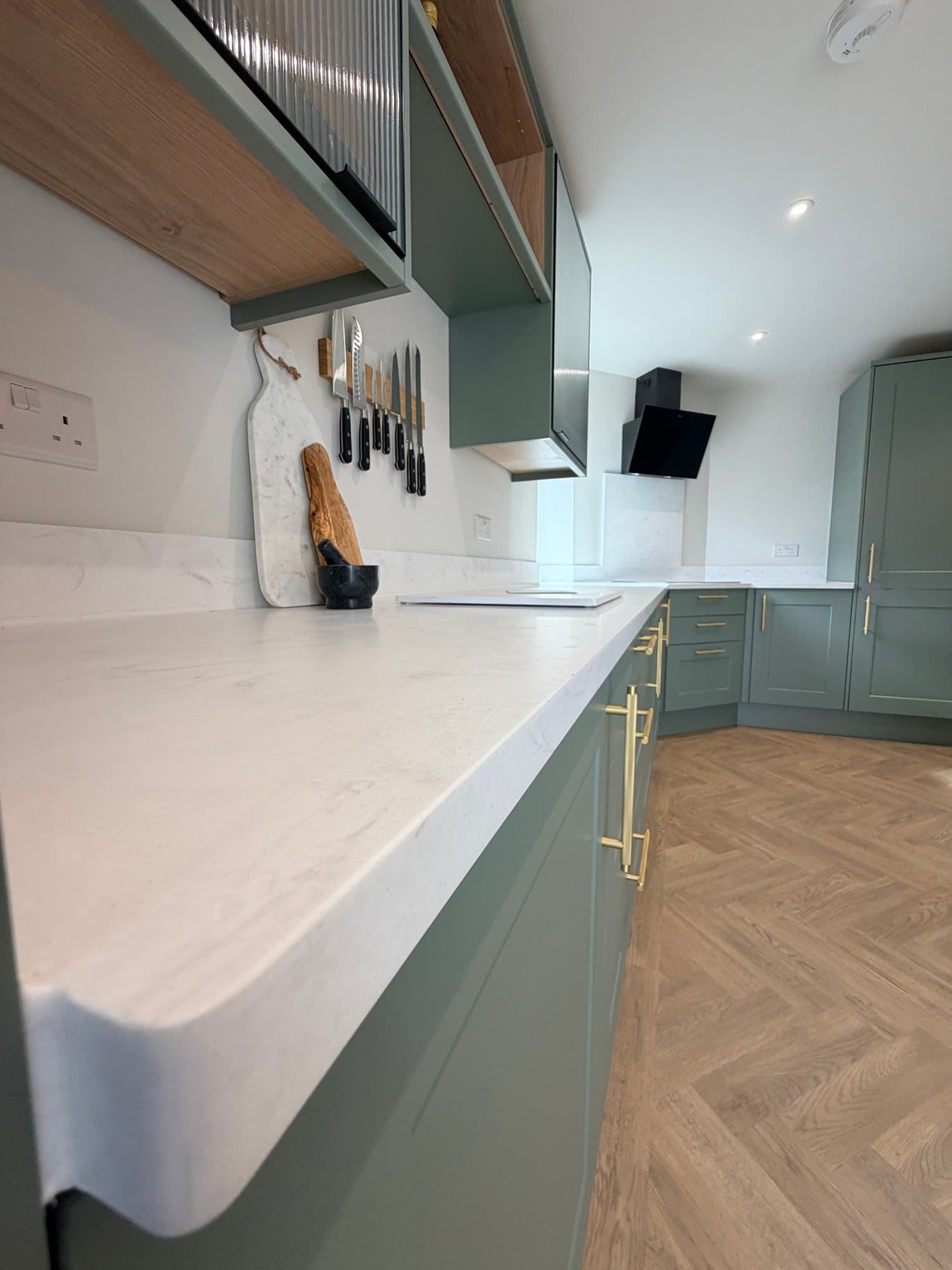 Marble-effect worktop and magnetic knife rail in a sage green fitted kitchen