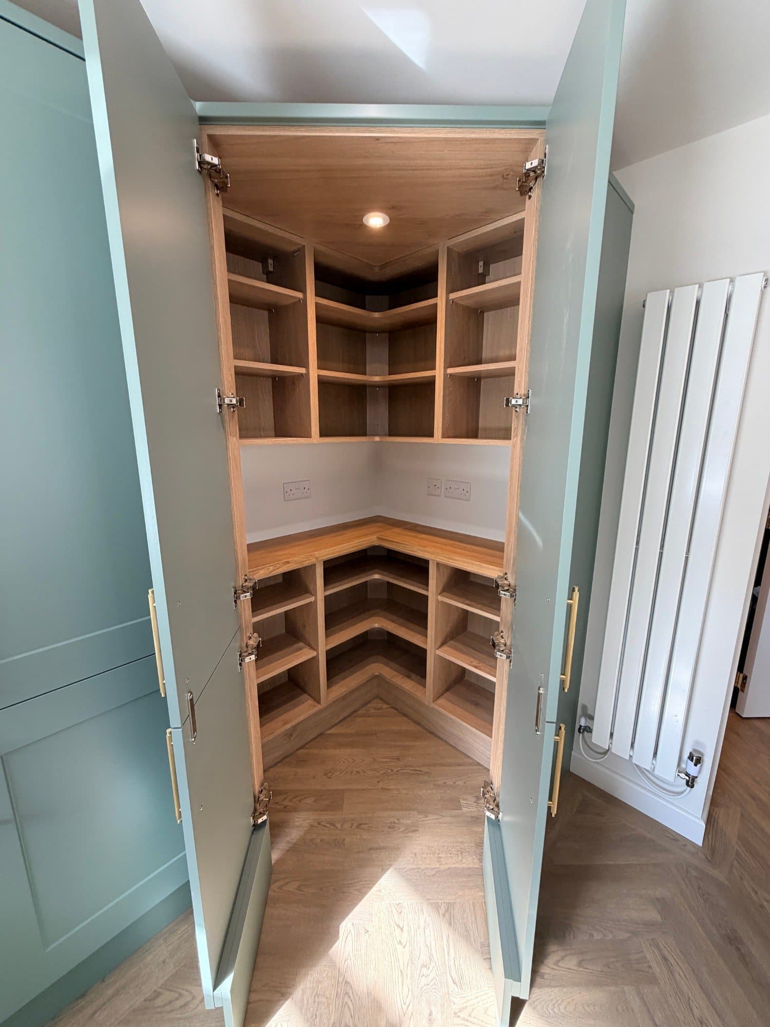 Open corner pantry cupboard with oak shelving and worktop