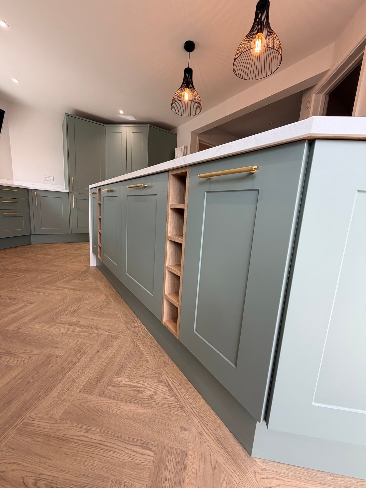 Kitchen island end panel with open oak shelving and a brass bar handle