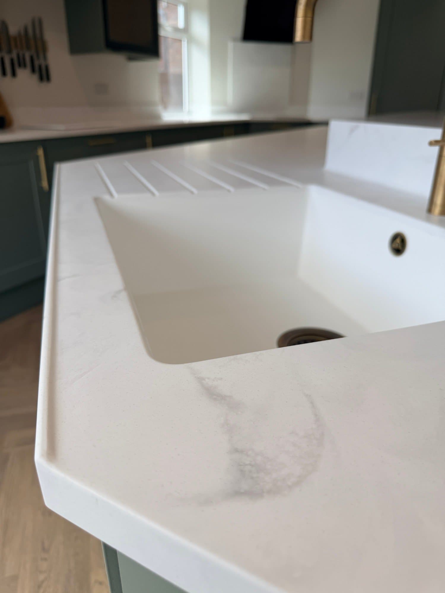 Sink and drainer with integrated drainage grooves in a white worktop