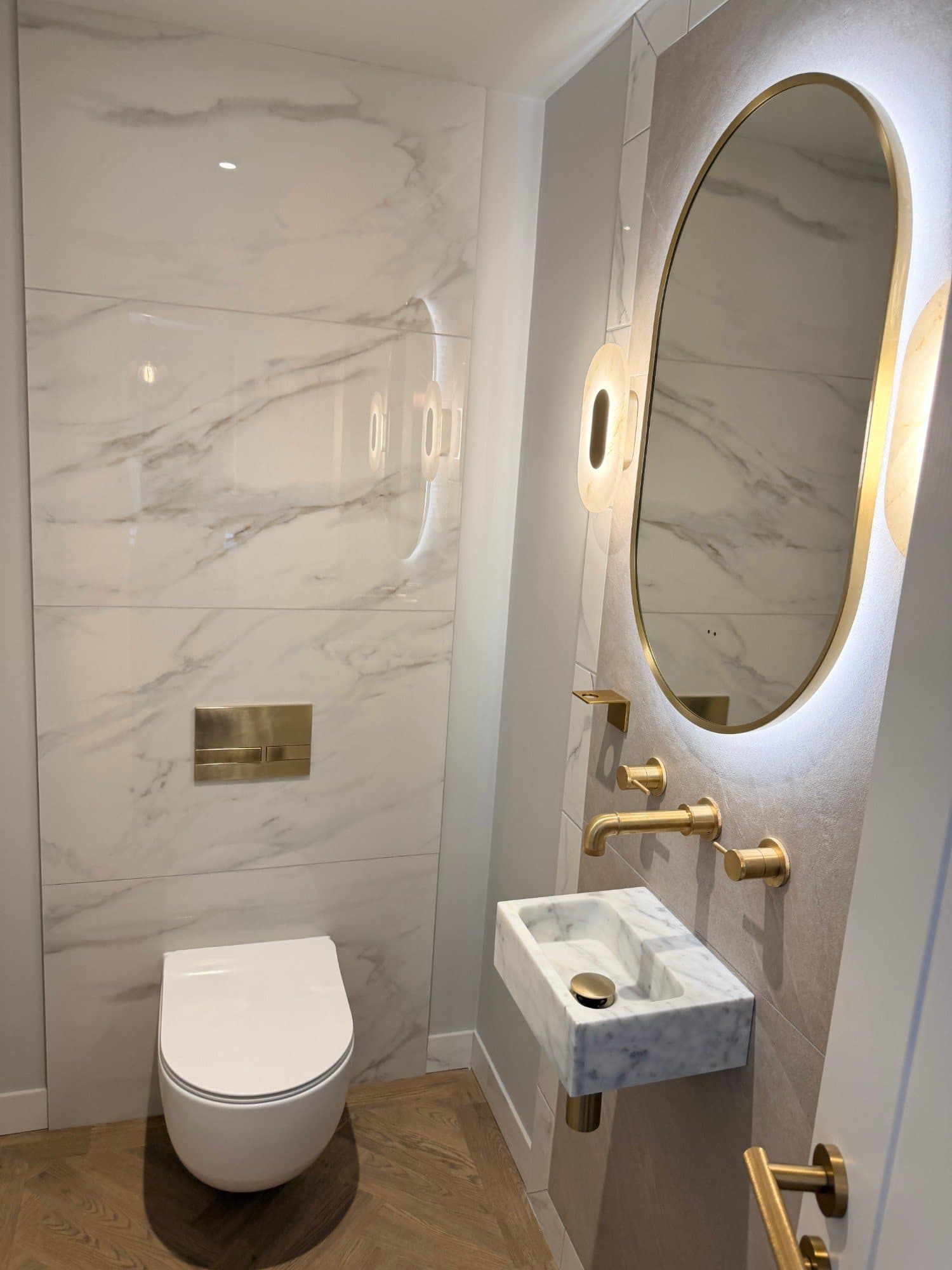 Downstairs WC with brass fittings, marble tiling and wall-hung sanitaryware