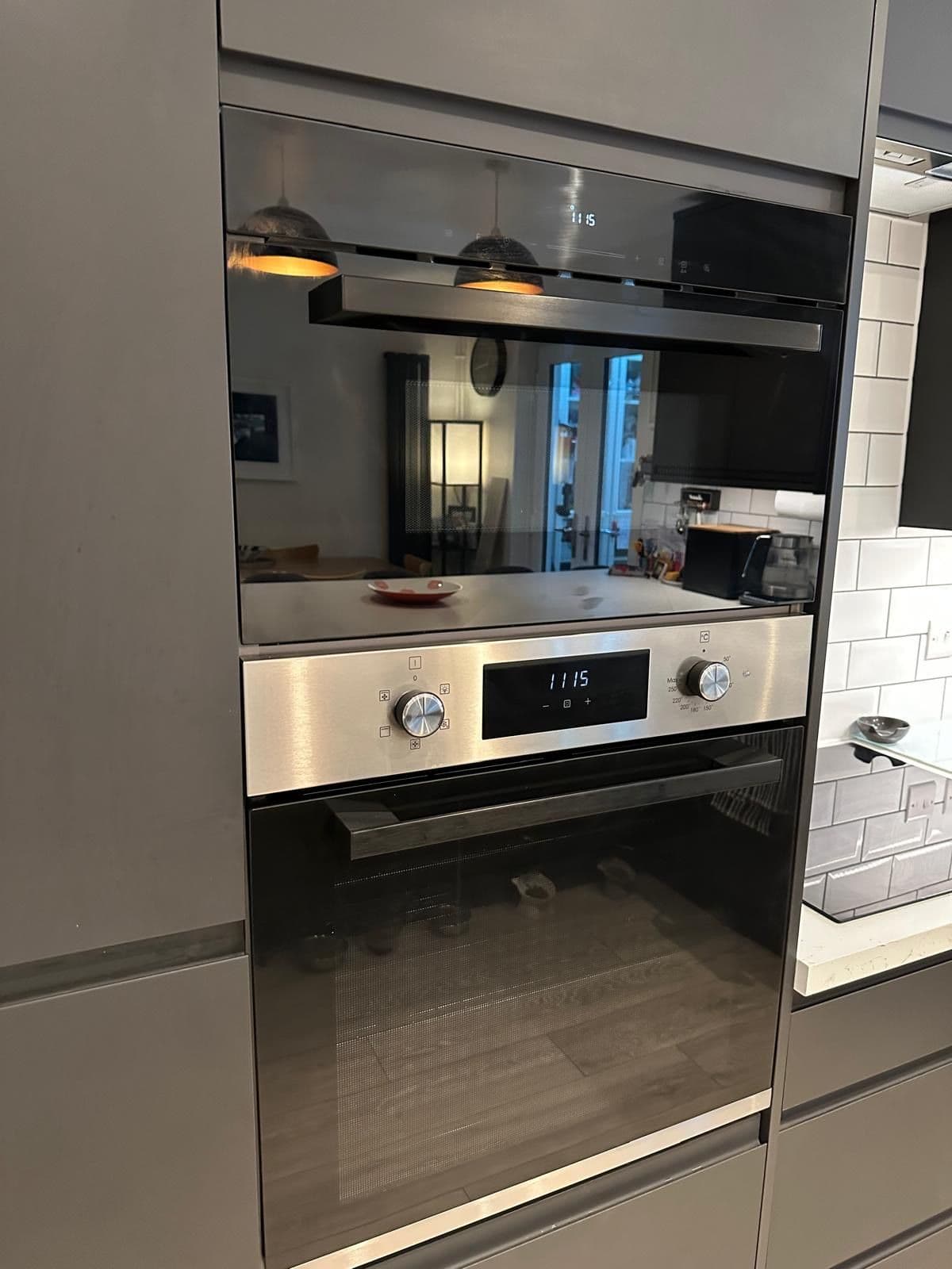Close up of a stainless steel and black built-in combination oven and microwave set into black cabinetry