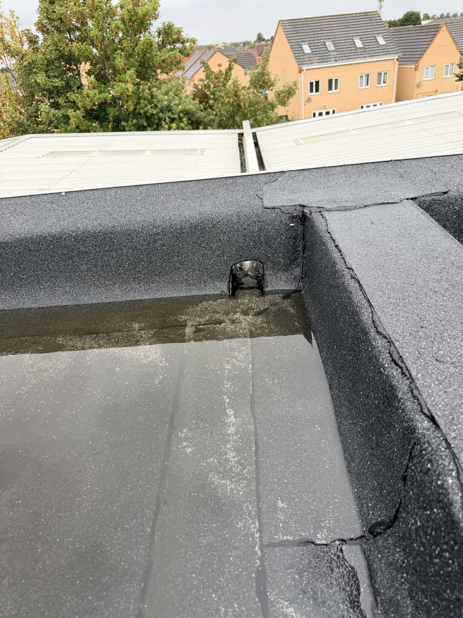 Close up of a split and cracked joint in the flat roof felt at a corner upstand, during the repair