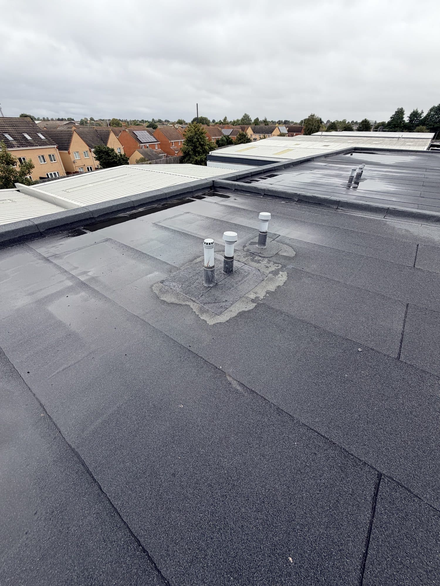Close up of three roof vent pipes with a grey sealant patch repair around their base