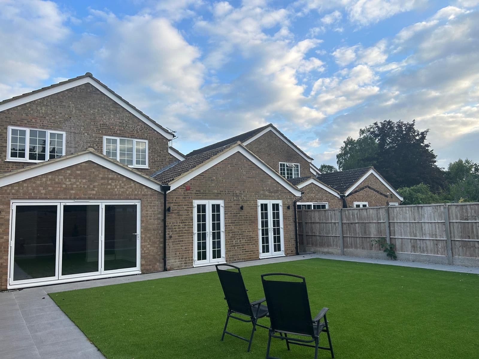 Rear of the house in the evening with two garden chairs on the artificial lawn