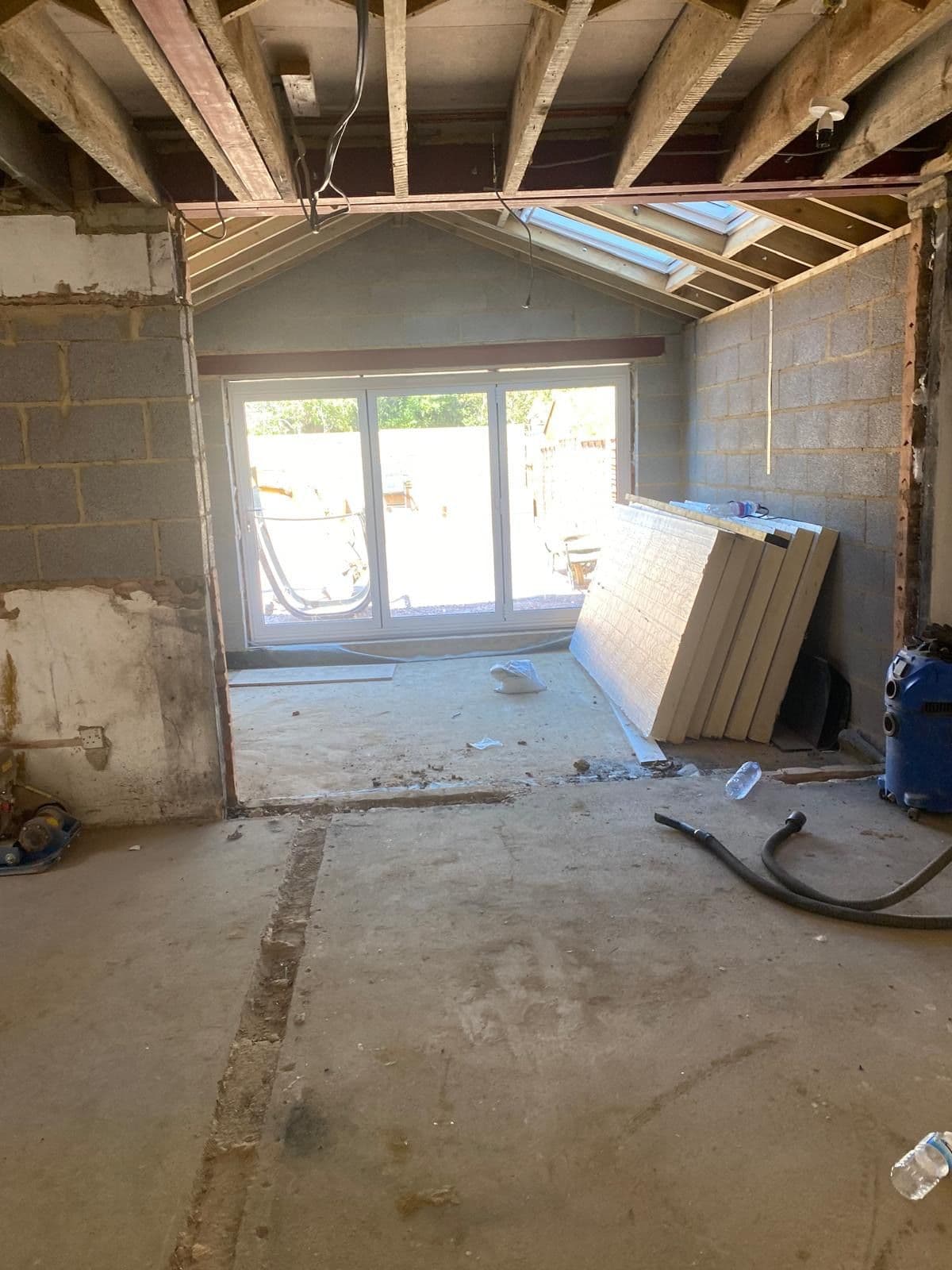 Rear extension under construction with blockwork walls, exposed roof trusses and bifold doors fitted into the opening
